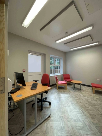 Group room with desk and computer and chairs around a smaller table